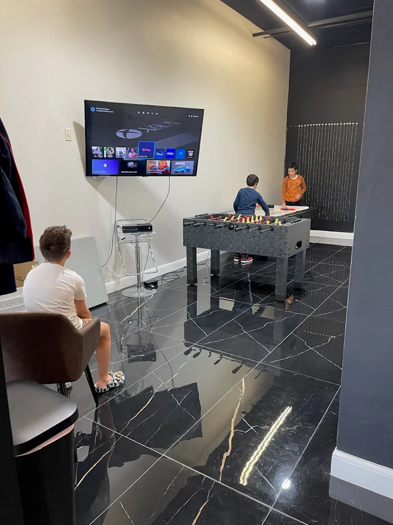 Lounge game room with Xbox, foosball, and air hockey at Amari's Barbershop